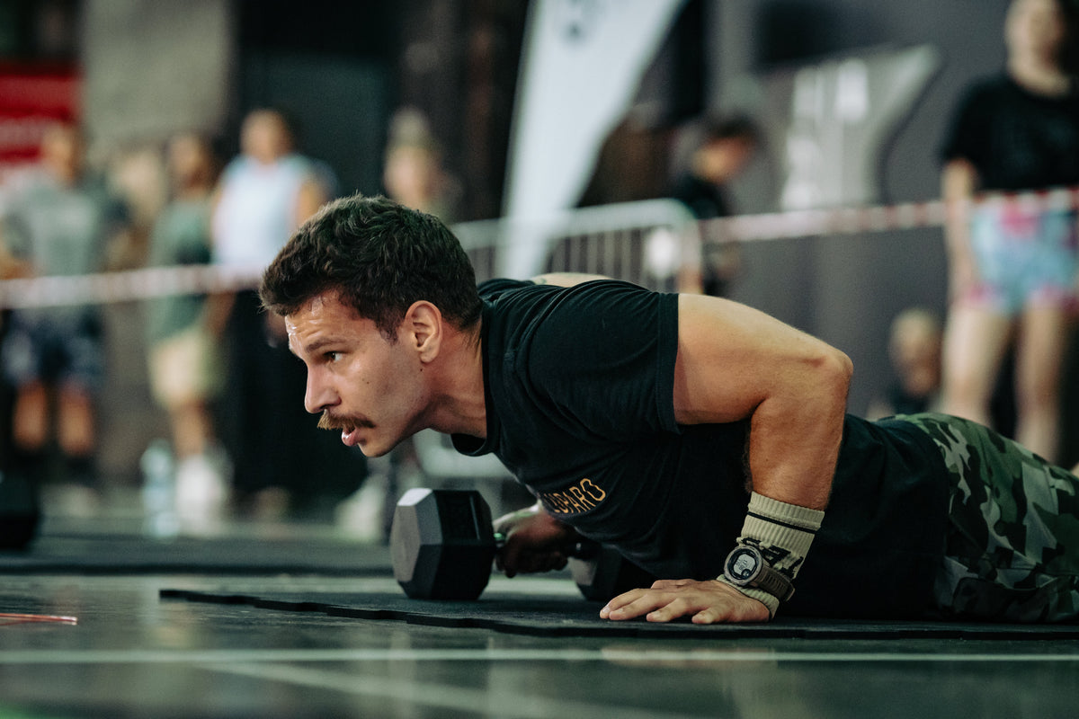 Athlet in Plank-Position mit Kurzhantel während einer Trainingseinheit